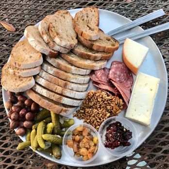 Bacchanal Fine Wine and Spirits signature dishes Guests can build their own cheese plates by choosing from a selection of cheeses, which are then served with olives, pickles, toasted bread, and chutney.